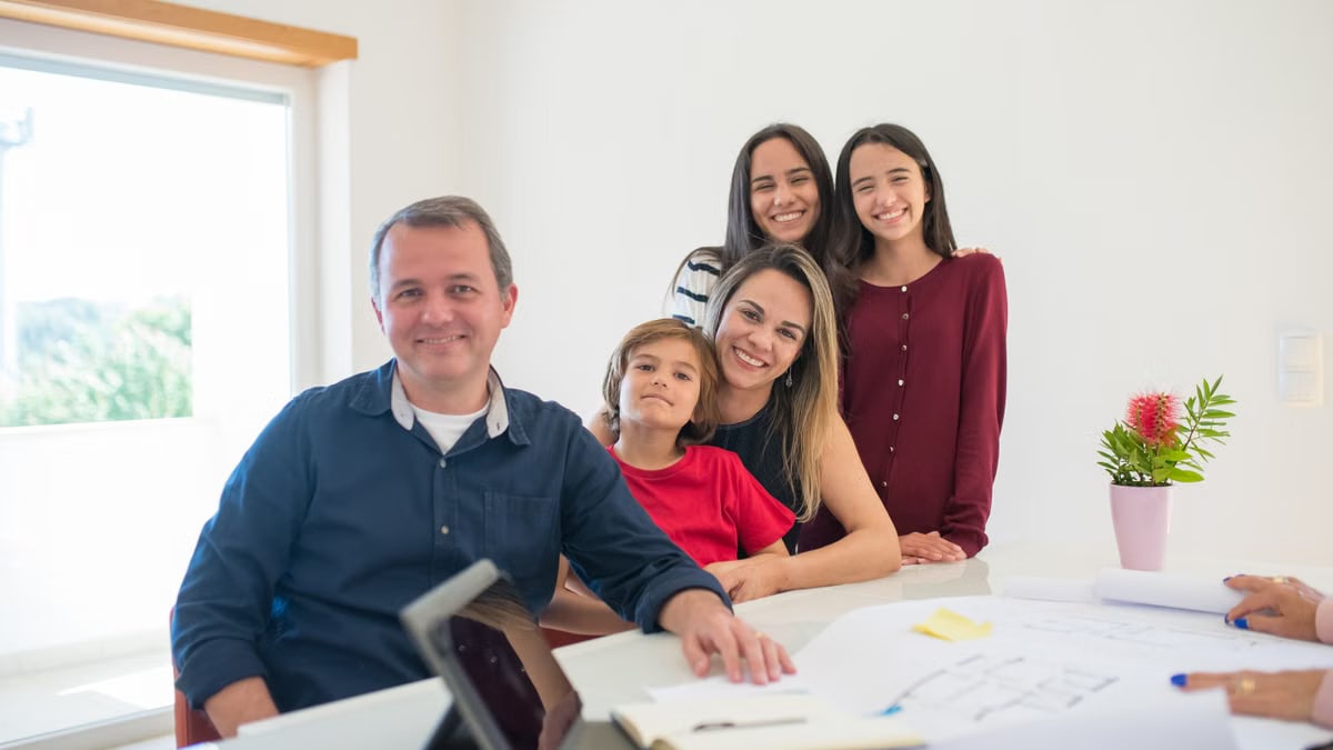 Smiling family at home with architectural plans, embracing warmth and togetherness.